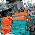 Cuộn lưới bao che công trình màu xanh ngọc và cam tại xưởng